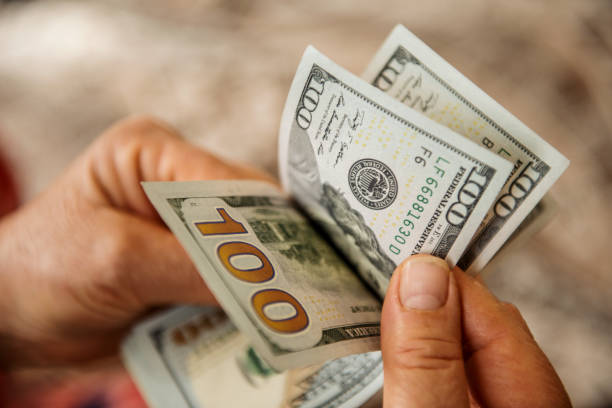 istock High angle view of unrecognizable person counting US Dollar bills 910155634