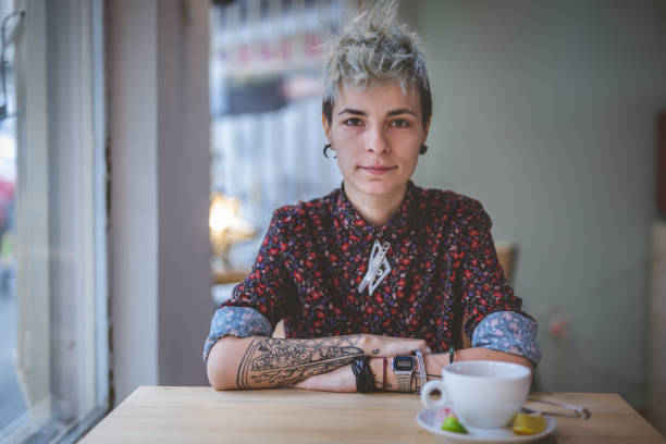 Gorgeous modern woman Young and lovely gender blend woman, enjoying a cup of coffee at the cafe. transgender person stock pictures, royalty-free photos & images