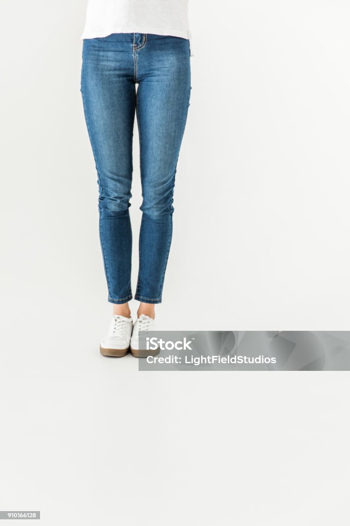woman in denim pants and shoes standing isolated on white low section of young woman in denim pants and shoes standing isolated on white Jeans Stock Photo
