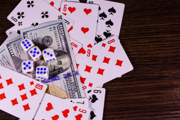 istock Playing cards, dice and one hundred dollar bills on a dark wooden table. Top view 910166486