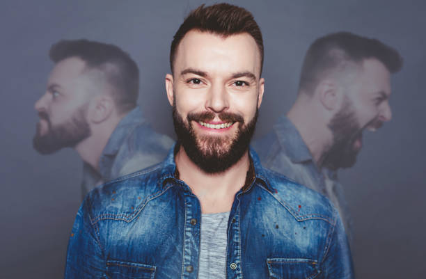 Concept of a split personality. Human inner world. Portrait of a beautiful smiling modern man against the backdrop of his split personality. Psychoanalysis. stock photo