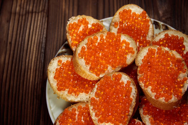 sandwiches con mantequilla y caviar rojo en mesa de madera - plank bread caviar close up fotografías e imágenes de stock