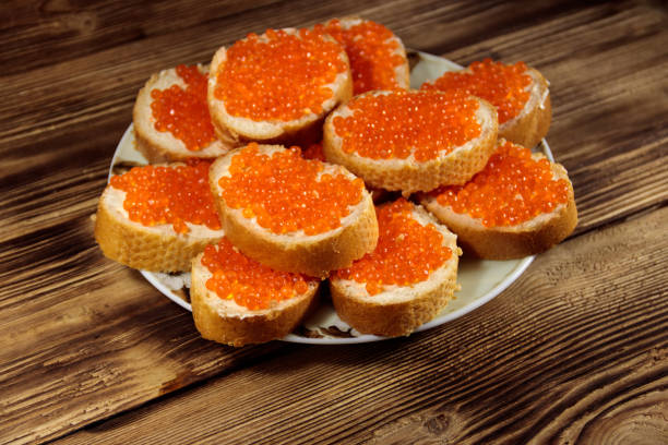 sandes com manteiga e caviar vermelho na mesa de madeira - plank bread caviar close up - fotografias e filmes do acervo