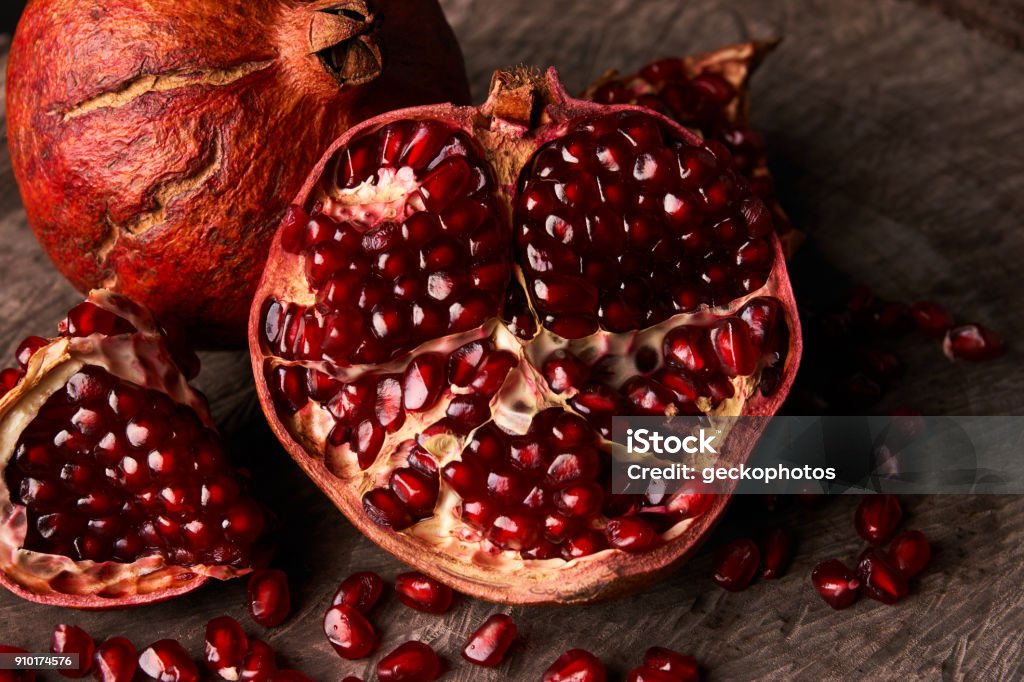 Ripe pomegranate fruit and pomegranate seeds Ripe pomegranate fruit and pomegranate seeds on dark background, close-up. Healthy vegetarian antioxidant organic diet food Above Stock Photo