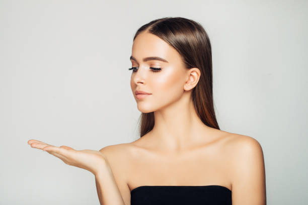 istock Smiling woman holding something on hand and demonstrating it 910177452