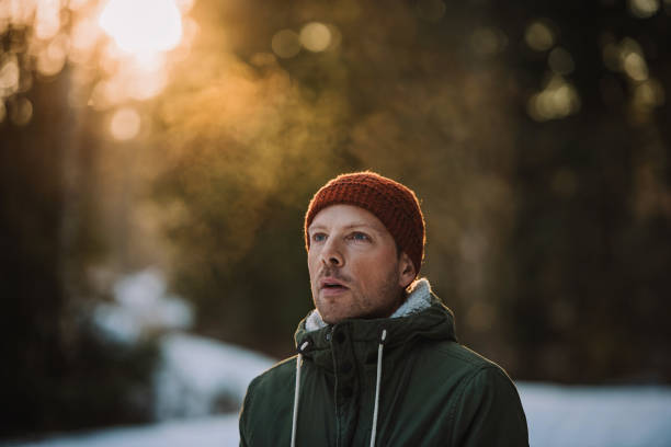 Close up of a handsome smiling young man wearing winter jacket walking outdoors