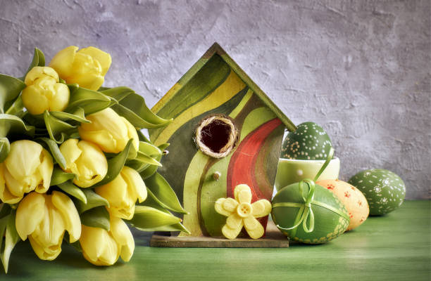 istock Yellow tulips, birdhouse and painted Easter eggs with decorative felt flower, text space 910195678