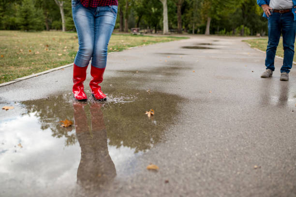 istock Rubber boots are jumping into a big puddle with splash. 910199056