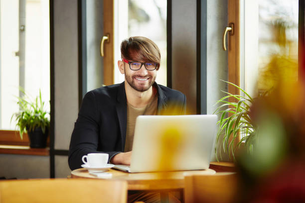 istock Cheerful man at laptop in cafe 910203558