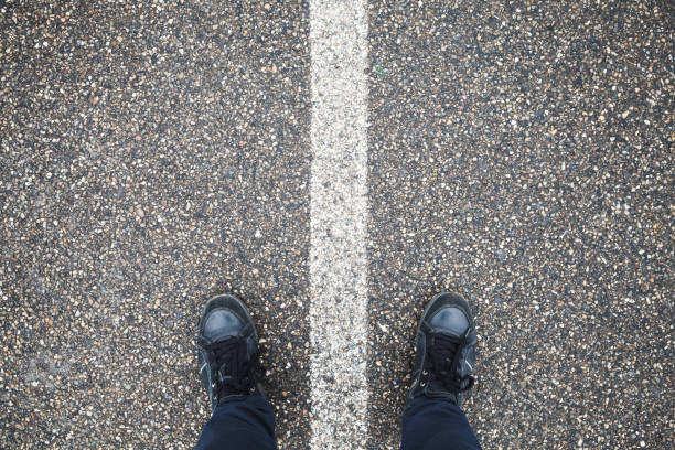 istock Male feet stand on asphalt with dividing line 910207190