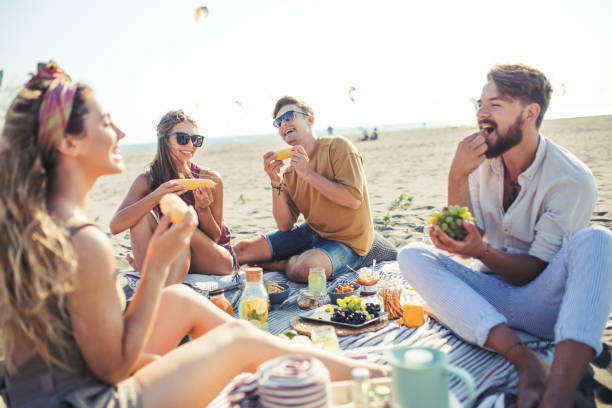 angenehmen strand picknick mit freunden - picknick stock-fotos und bilder