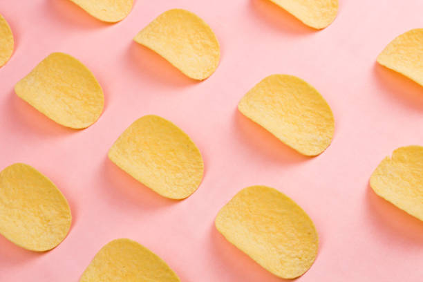 kartoffelchips auf pastell rosa hintergrund im minimalismusstil. - potato chip stock-fotos und bilder