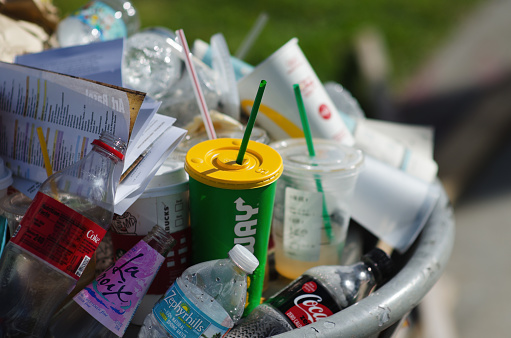 Miami - December 6, 2017: Consumer trash from fast-food chains, drinks brands, and plastic water bottles overflows from a public garbage can on the street outside Art Basel Miami Beach art fair.