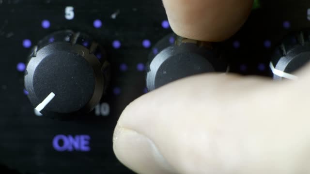 Male fingers turning headphone amplifier knob