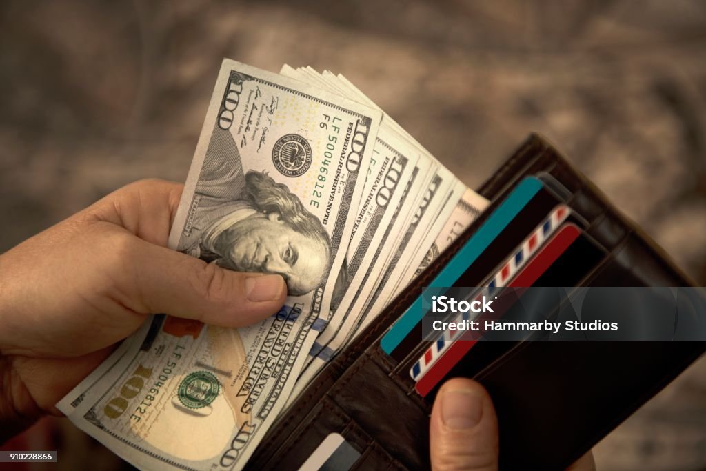 High angle view of unrecognizable mature man placing USA Dollar bills into wallet High angle view of unrecognizable mature man placing USA Dollar bills into wallet. Horizontal composition. Image taken with Nikon D800 and developed from Raw format. US Paper Currency Stock Photo