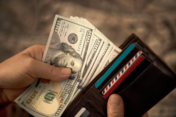 High angle view of unrecognizable mature man placing USA Dollar bills into wallet High angle view of unrecognizable mature man placing USA Dollar bills into wallet. Horizontal composition. Image taken with Nikon D800 and developed from Raw format. large group of objects stock pictures, royalty-free photos & images