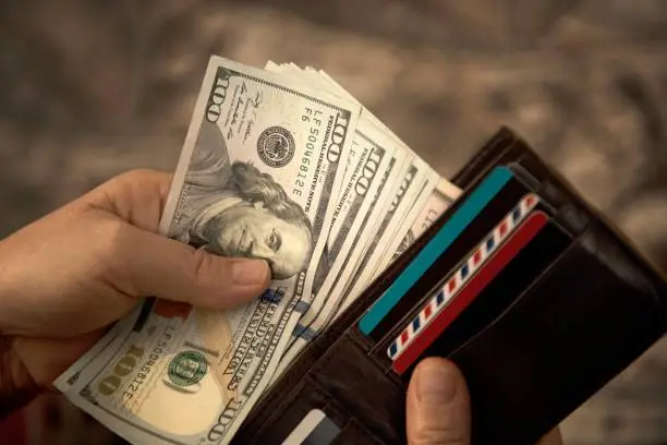 Photo of High angle view of unrecognizable mature man placing USA Dollar bills into wallet
