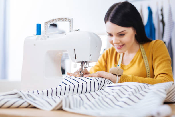 istock Experienced skilled tailor sitting at the sewing machine and making a blouse 910235736