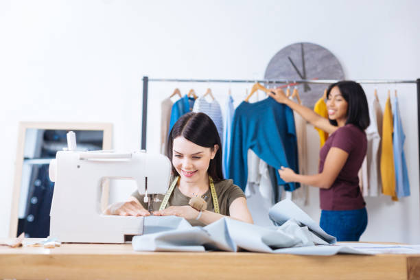 istock Skilled young woman sewing while her coworker standing behind her back 910238610
