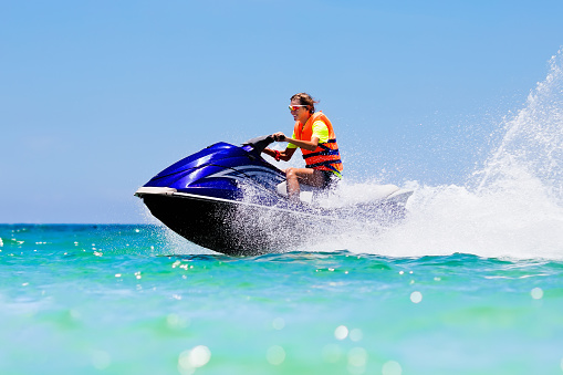 Teenager on jet ski. Teen age boy skiing on water scooter. Young man on personal watercraft in tropical sea. Active summer vacation for school child. Sport and ocean activity on beach holiday.