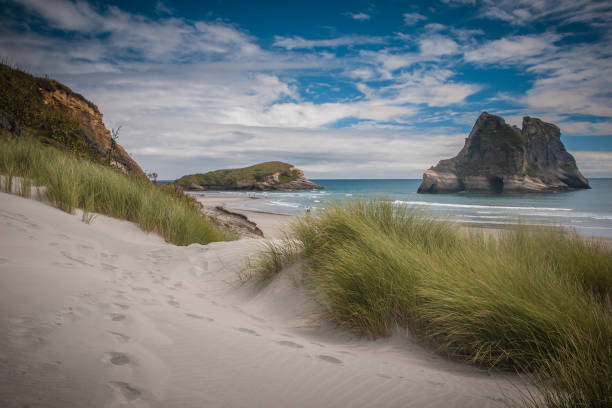 One of the Archway Islands off the coast of Wharariki Beach, Cape Farewell, South Island, New Zealand. Beach with beach pools in foreground