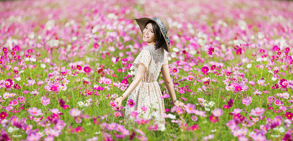 Woman running in the garden flowers Cosmos flowers to touch her. On a clear day