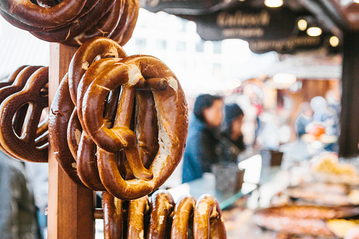 Celebration of the famous German beer festival Beer Fest. Traditional pretzels called Brezel hang on the stand against the background of a blurred street market and people on holiday.