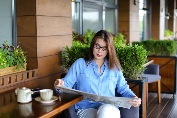 istock Charming woman reading newspaper at restaurant and drinking tea 910311068