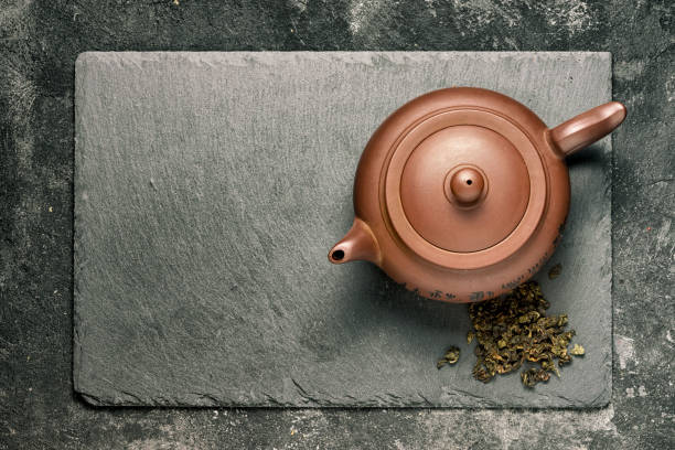 istock Brown ceramic teapot on black stone tray, top view. 910311330
