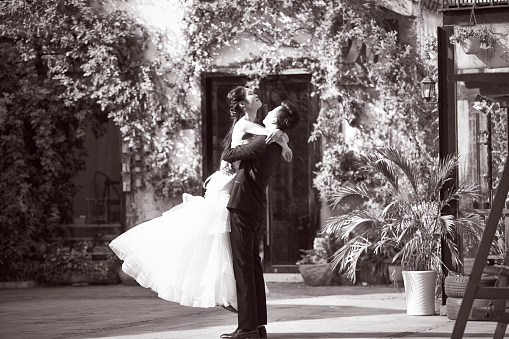 asian newly wed bride and groom celebrating marriage outside a building, black and white.