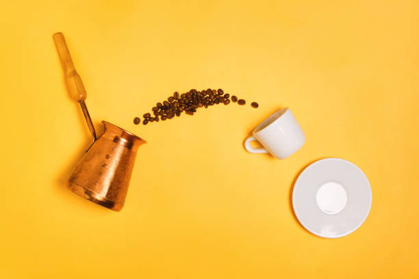 istock Coffee beans falling from Turkish cezve into the espresso cup, concept of coffee making and drinking. Yellow background, flatlay 910326232