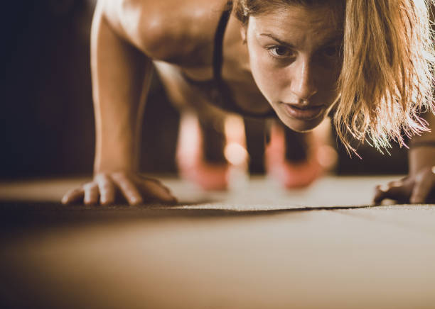 Concentrated female athlete exercising push-ups in a gym. Copy space.