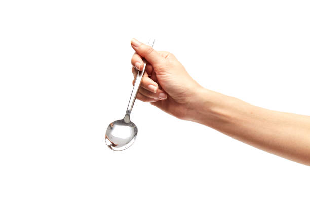 istock woman's right hand holds a spoon on a white background. 910336520
