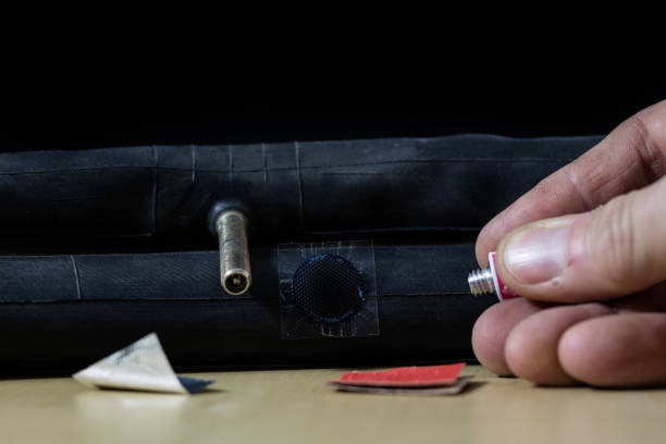 istock Bicycle breakdown during the trip. Sticking a bicycle tube in a workshop. Mechanic fixing a bicycle tube. Workshop table and tools. 910336790
