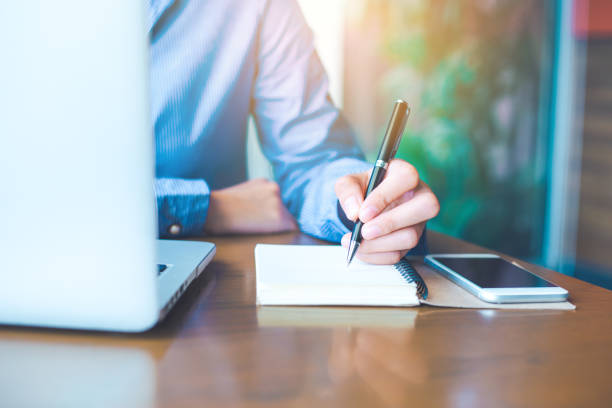 istock Business woman hand is writing on notepad with pen in office. 910336916