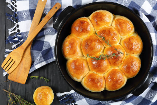 soft and fluffy homemade dinner rolls freshly baked soft and fluffy homemade dinner rolls in baking dish with kitchen towel and spatulas on wooden kitchen table, view from above, close-up rolled up stock pictures, royalty-free photos & images