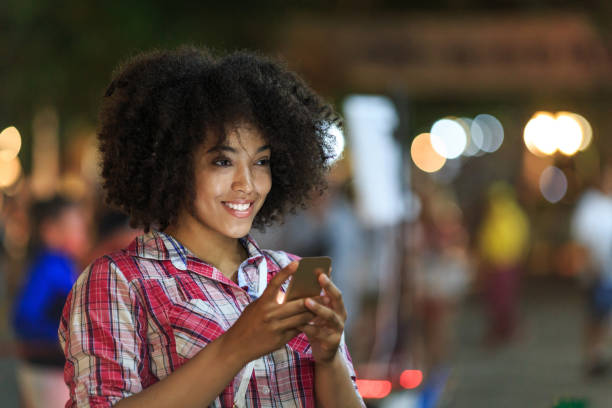istock Smiling woman using smart phone at night on street 910343342