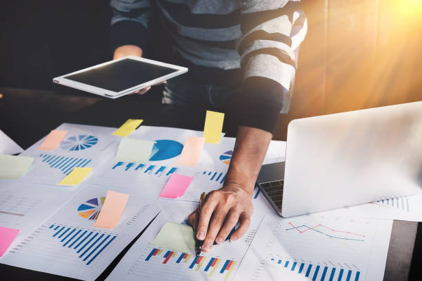istock business man holding  digital tablet and use laptop to working document accountant analyze income & budget & tax is are planning a marketing plan to improve the quality of their sales in the future. 910343534