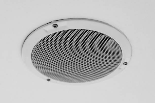 White round circle speaker and grille hanging on white ceiling. Selective focus stock photo