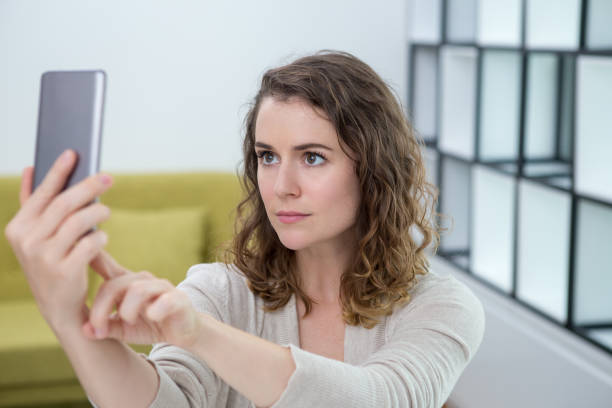 istock Serious Young Woman Taking Selfie at Home 910348998