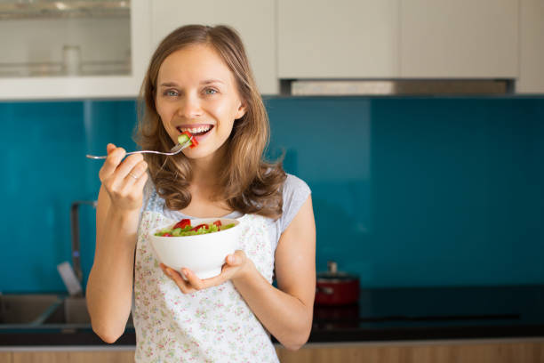 istock Happy Woman Eating Vegetable Salad in Kitchen 910362916