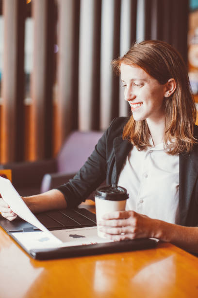 istock Smiling Woman Working and Drinking Coffee in Cafe 910366738