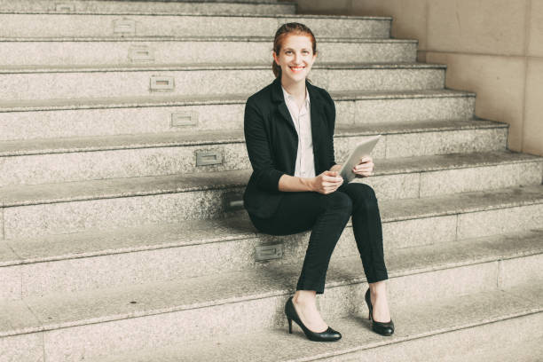 istock Smiling Business Woman Using Tablet on Stairs 910366740