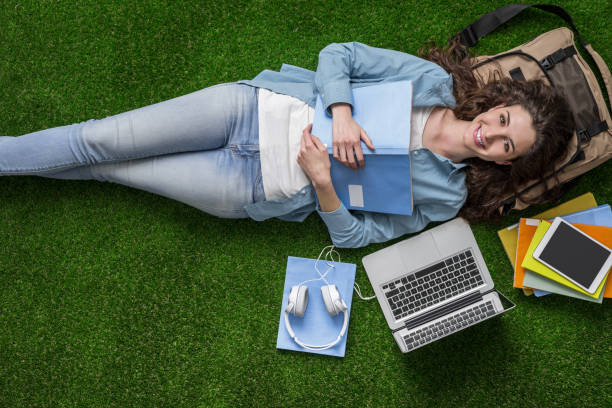 student relaxing on the grass - lying down women laptop freedom imagens e fotografias de stock