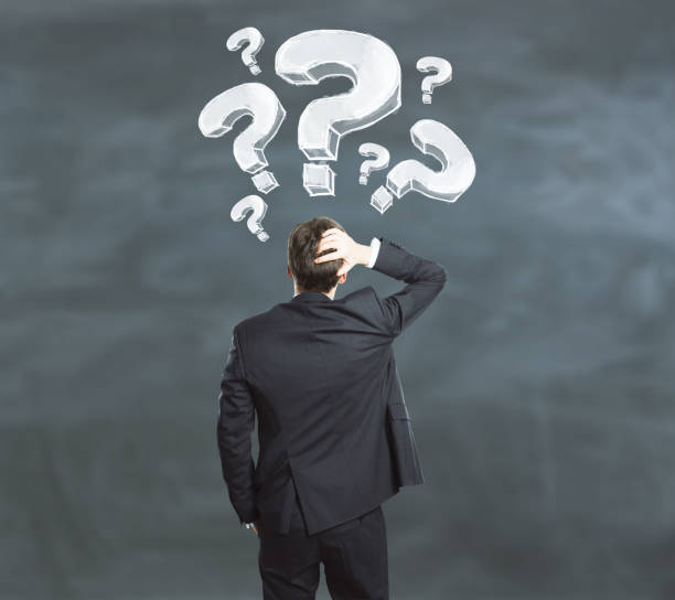 istock businessman on chalkboard background looking at drawn question marks 910371190