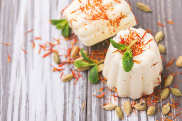 Indian kulfi dessert, ice cream with safron, mint, nuts Traditional Rajasthani Indian cuisine. Homemade kulfi dessert, ice cream with safron, mint and nuts on gray wooden background. Copyspace, top view. mithai stock pictures, royalty-free photos & images