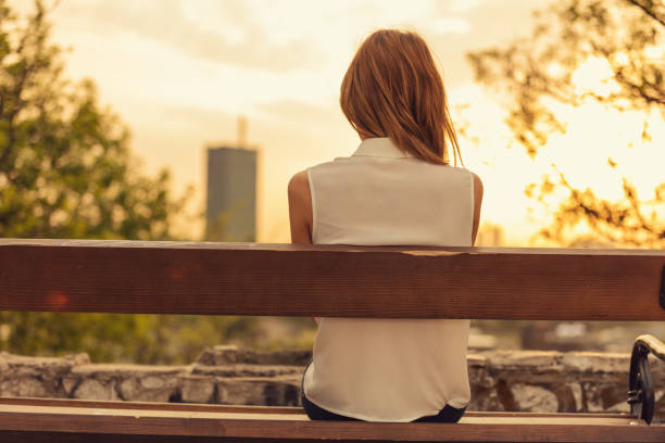 istock Woman sitting on a bench and watching the distant city scenery. 910386854