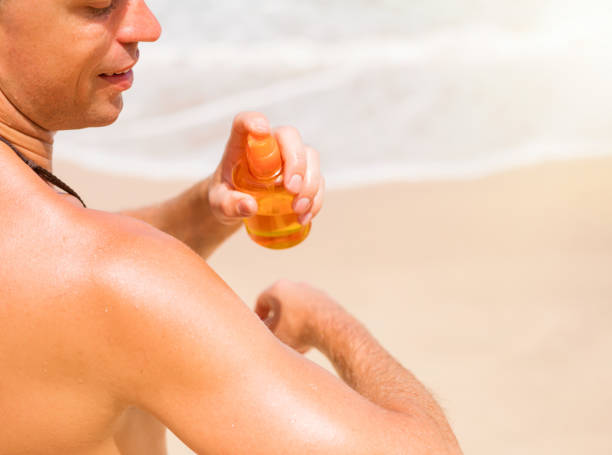 istock Man spraying sun lotion on skin 910387056