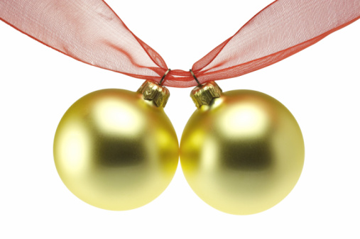 Three pink and golden colored christmas baubles hanging with shiny ropes.