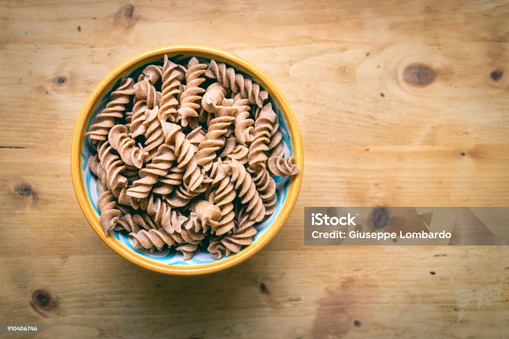 Plato de cerámica lleno de pasta fusilli integral cruda - Foto de stock de Grano entero libre de derechos